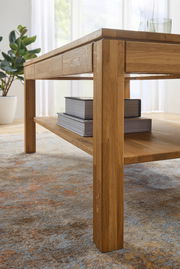 Nahaufnahme eines Couchtisches aus Holz mit Bücherstapel auf der unteren Ablage, seitliche Perspektive.