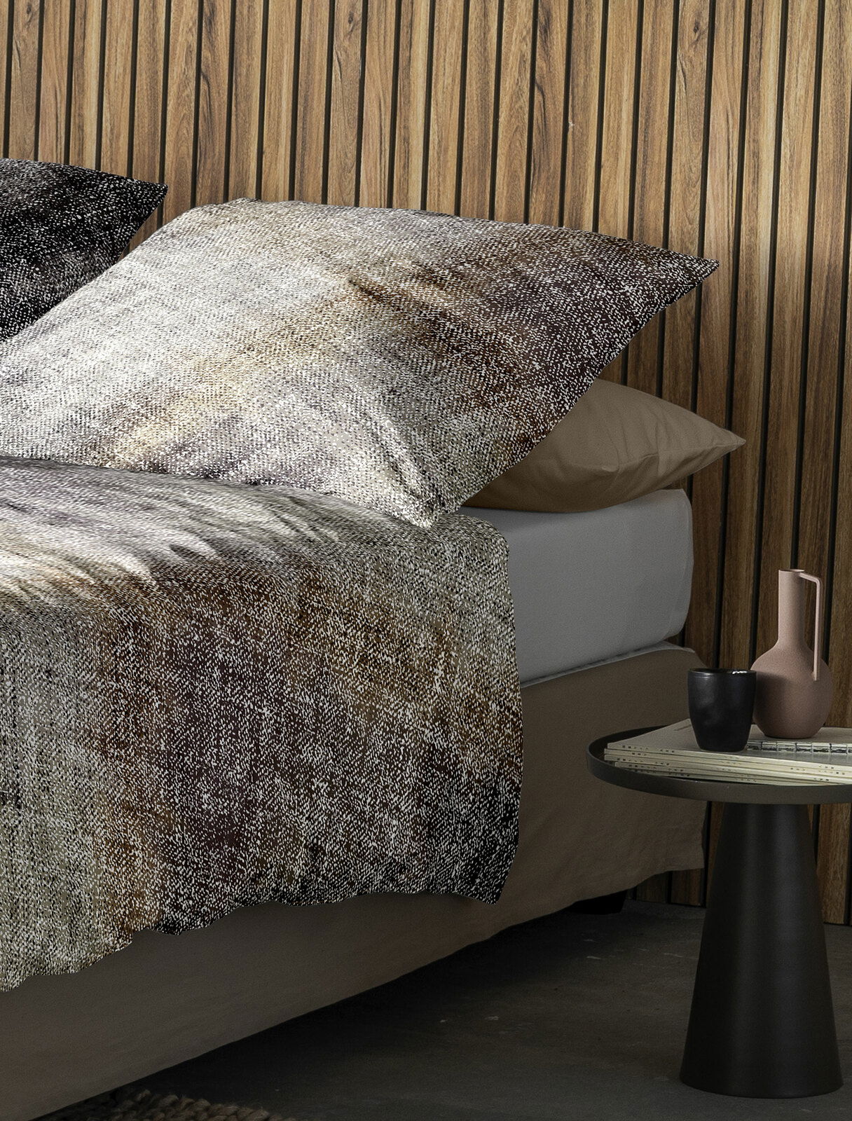 Bettwäsche-Set in natürlichen Erdtönen mit Kissen und Decke auf einem Bett, seitliche Perspektive