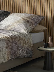 Bettwäsche-Set in natürlichen Erdtönen mit Kissen und Decke auf einem Bett, seitliche Perspektive