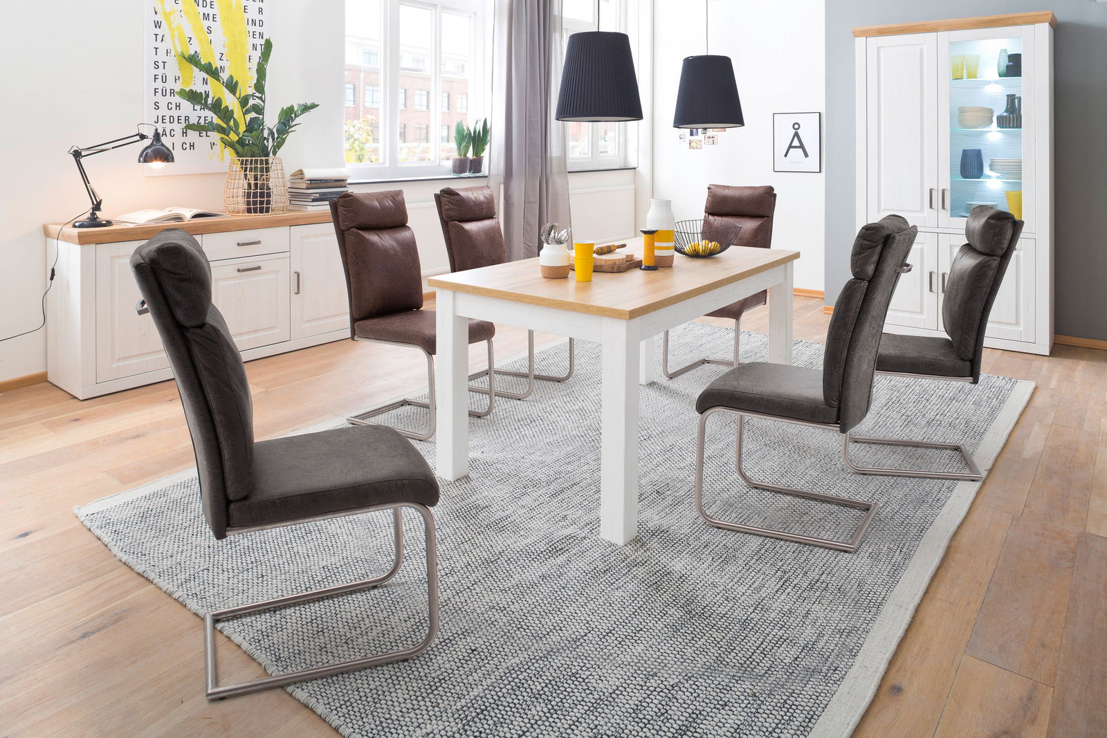 Esszimmer mit modernem Tisch und Stühlen, im Hintergrund eine Kombi-Vitrine, seitliche Perspektive.