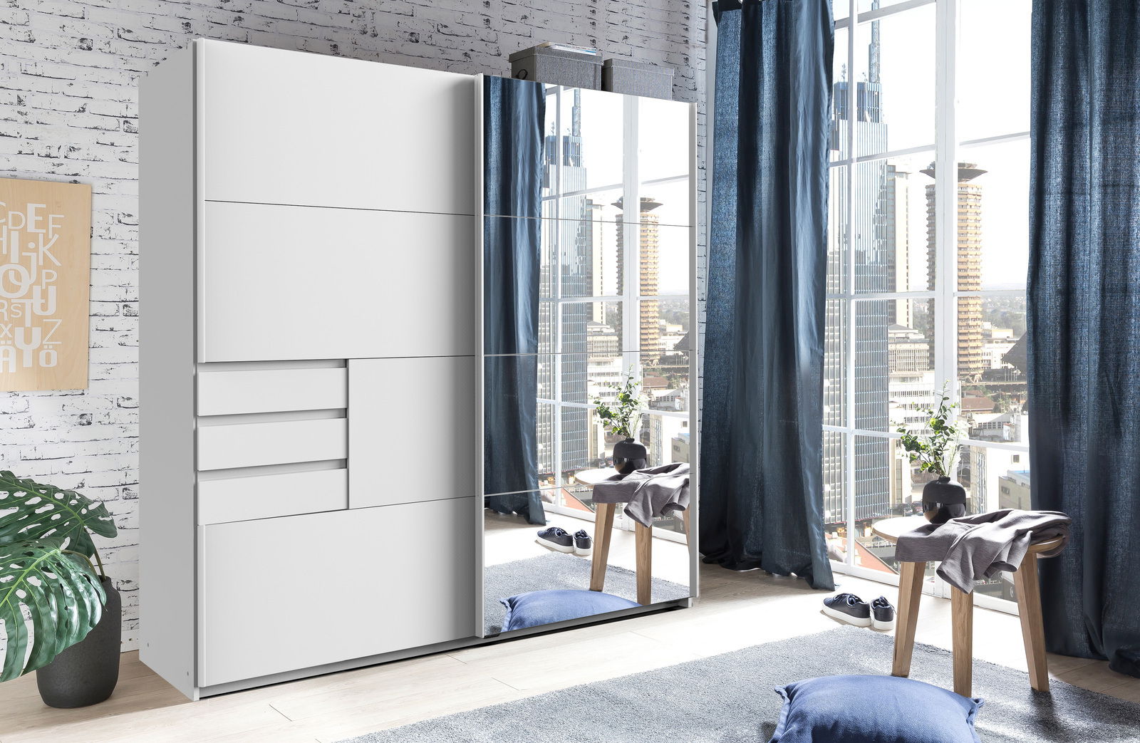 Z2 Schwebetürenschrank 2-trg. OLDENBURG Moderner Schwebetürenschrank mit zwei Türen, eine davon mit Spiegel, in einem hellen Raum mit großen Fenstern und urbanem Ausblick, aus der Perspektive von vorne links.