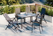 Moderner Gartentisch mit vier Stühlen auf einer Terrasse, umgeben von Pflanzen, mit Blick auf die Berge. Perspektive von schräg oben.