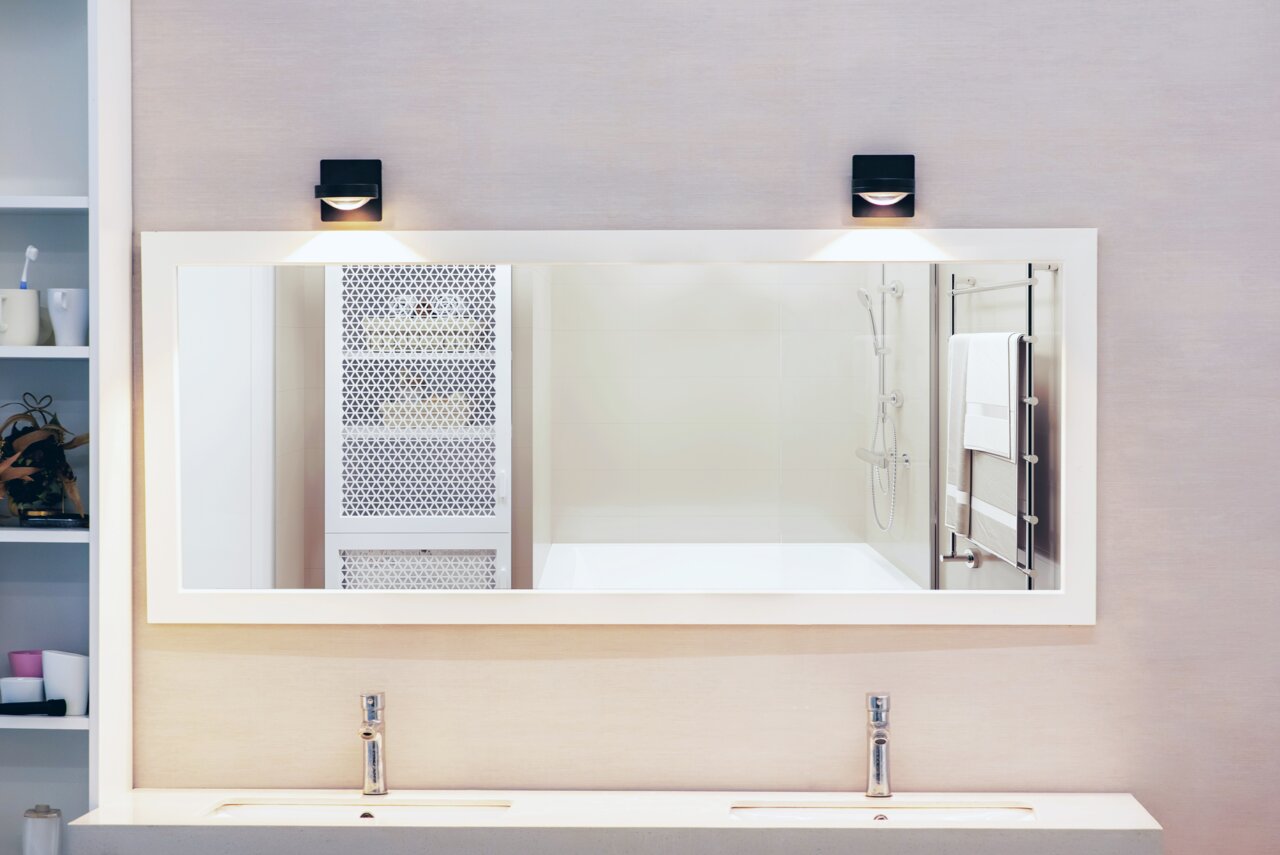 Megatron LED-Wandleuchte SOLO PUNTO - DOWN Moderne LED Wandleuchte über einem großen Spiegel im Badezimmer, frontal betrachtet.