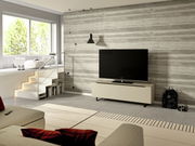 Modernes TV-Lowboard der Serie BORMIO in einem stilvollen Wohnzimmer, frontal betrachtet, mit einem großen Fernseher darauf und einer Betonwand im Hintergrund.