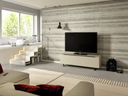 Modernes TV-Lowboard der Serie BORMIO in einem stilvollen Wohnzimmer, frontal betrachtet, mit einem großen Fernseher darauf und einer Betonwand im Hintergrund.