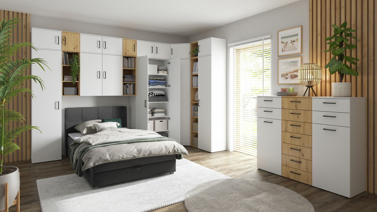 Moderne Schlafzimmermöbel mit weißen und holzfarbenen Schränken, Kommoden und Regalen, perspektivisch von vorne rechts aufgenommen.