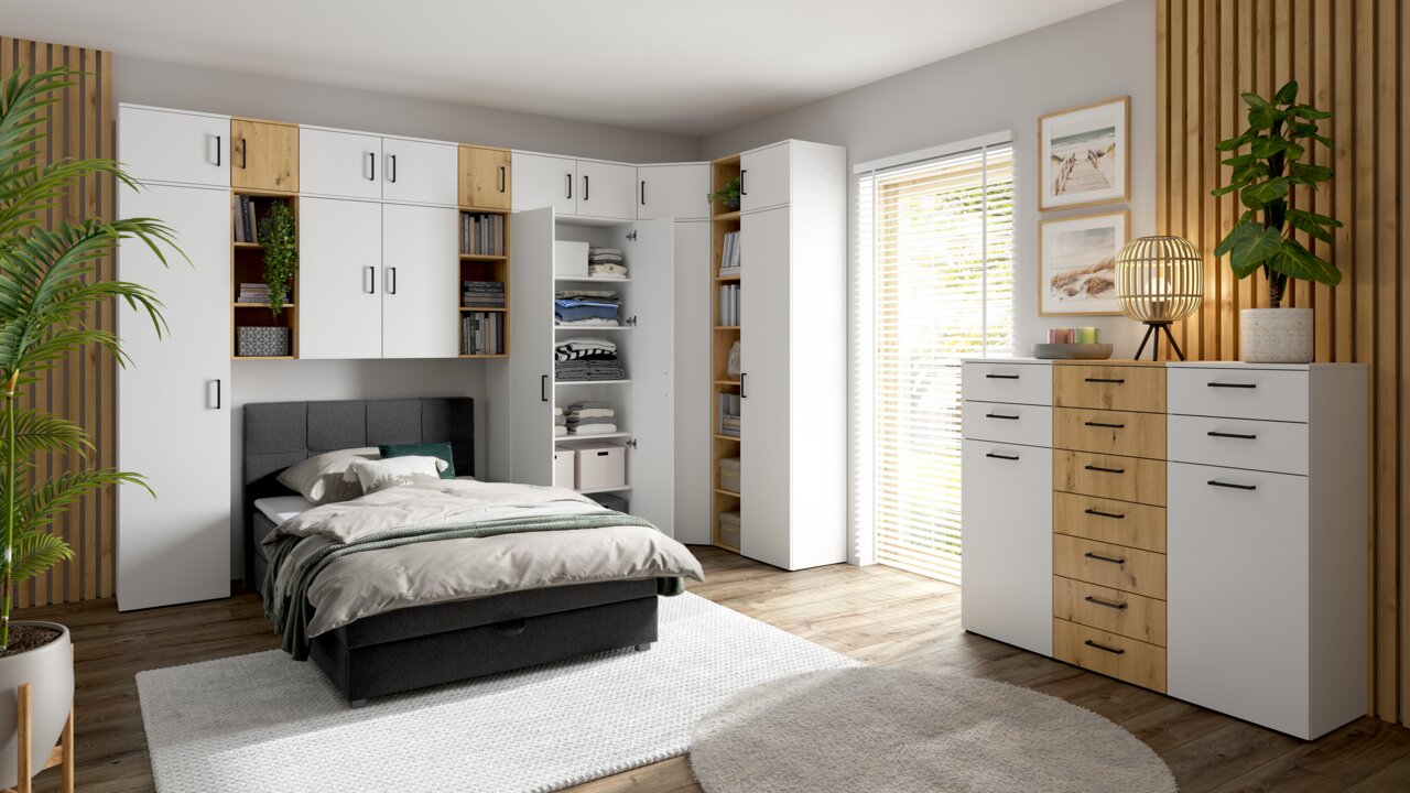 Moderne Schlafzimmermöbel mit weißen und holzfarbenen Schränken, Kommoden und Regalen, perspektivisch von vorne rechts aufgenommen.