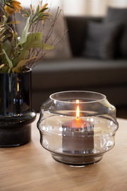 Glasvase oder Windlicht mit brennender Kerze, seitliche Perspektive auf einem Tisch.