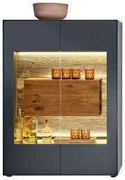 Frontale Ansicht eines modernen Highboards mit Glasvitrine, beleuchtetem Innenraum und dekorativen Gläsern und Flaschen.