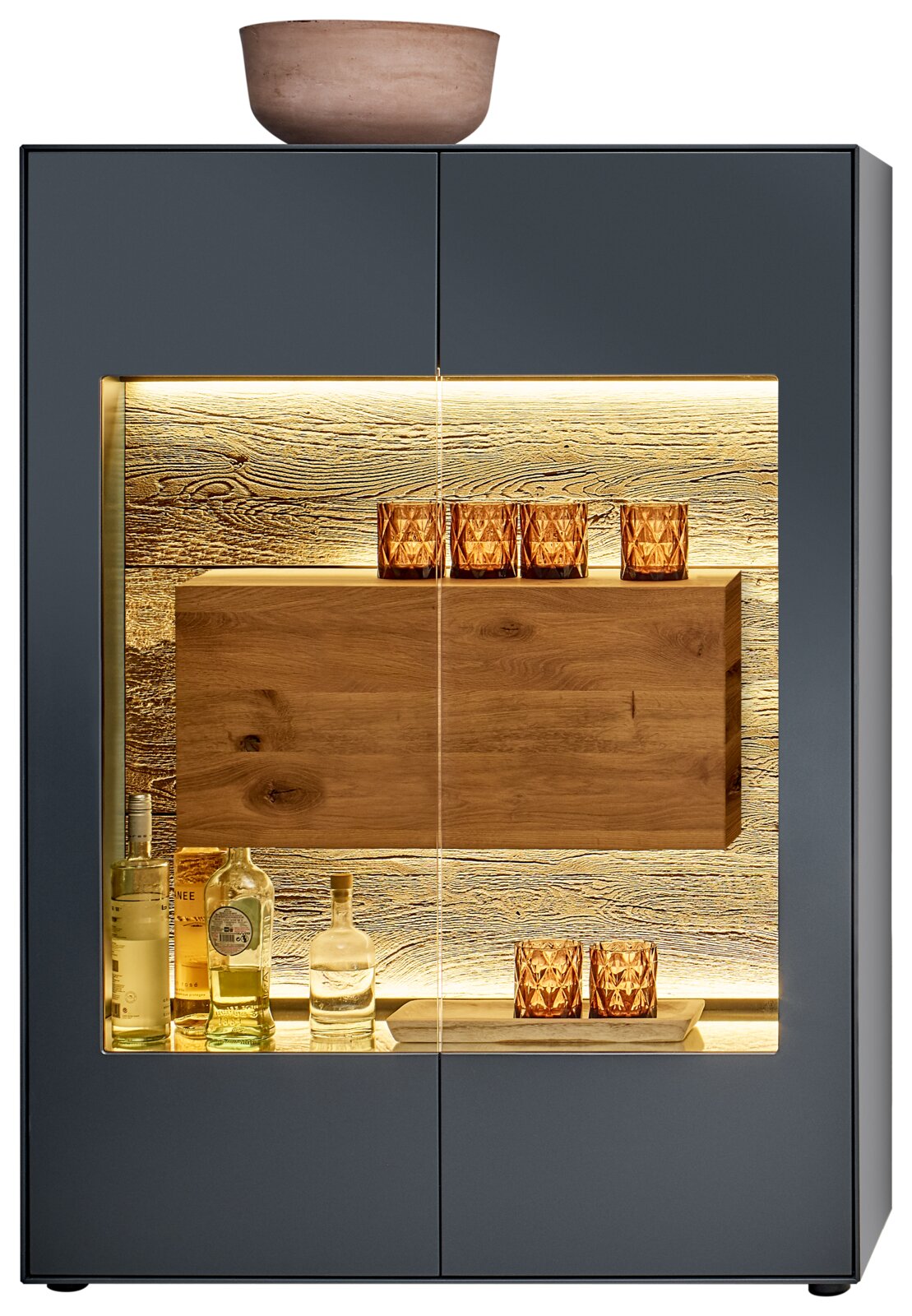 Vooraanzicht van een modern hoogkast met glazen vitrine, verlichte binnenruimte en decoratieve glazen en flessen.