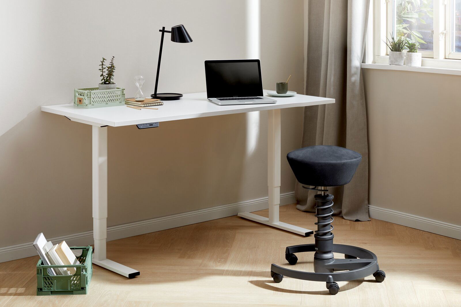 Moderner E-Schreibtisch in einem hellen Raum, ausgestattet mit einem Laptop, einer Lampe und Dekorationen. Perspektive von der Seite.