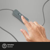 Nahaufnahme eines Fingers, der einen grauen Kippschalter auf einem Kabel betätigt, perspektivisch von oben.