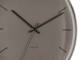Nahaufnahme einer modernen Wanduhr mit dunklem Zifferblatt und minimalistischen schwarzen Zeigern, seitliche Perspektive.
