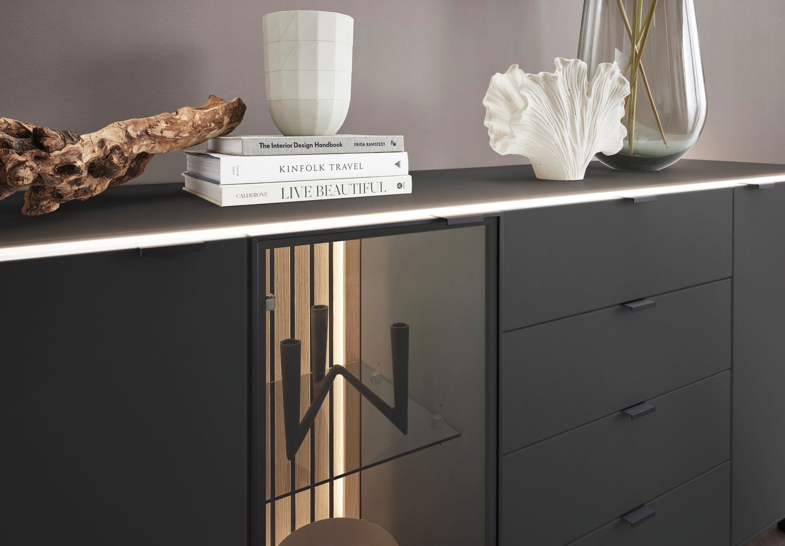Modernes Sideboard in dunklem Design mit dekorativen Elementen und Büchern auf der Oberseite, seitliche Perspektive.