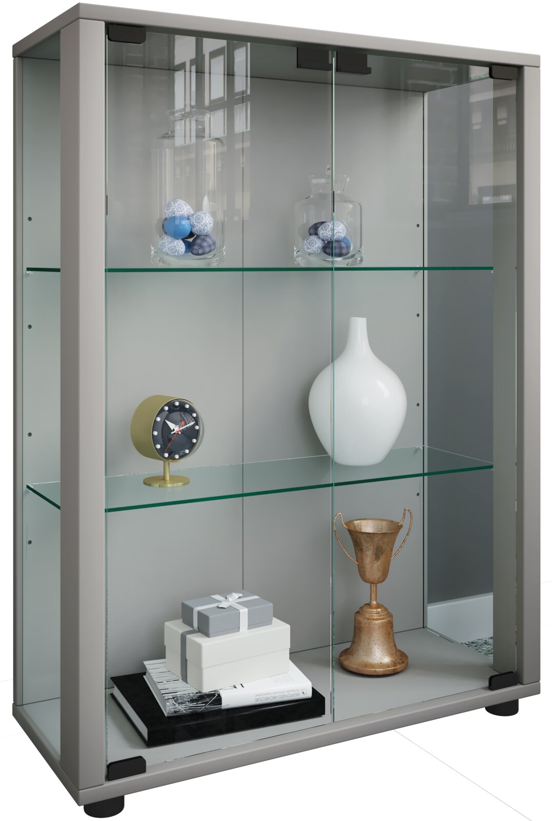 Graue Glasvitrine mit zwei Glasböden und Schiebetüren, befüllt mit Deko (Vasen, Uhr, Pokal, Geschenkboxen), in leicht schräger Frontansicht von links.