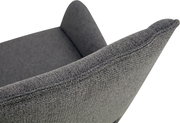Nahaufnahme eines dunkelgrauen, strukturierten Polsterstuhls mit geschwungener Rückenlehne und sichtbarer Naht, schräg von oben seitlich fotografiert