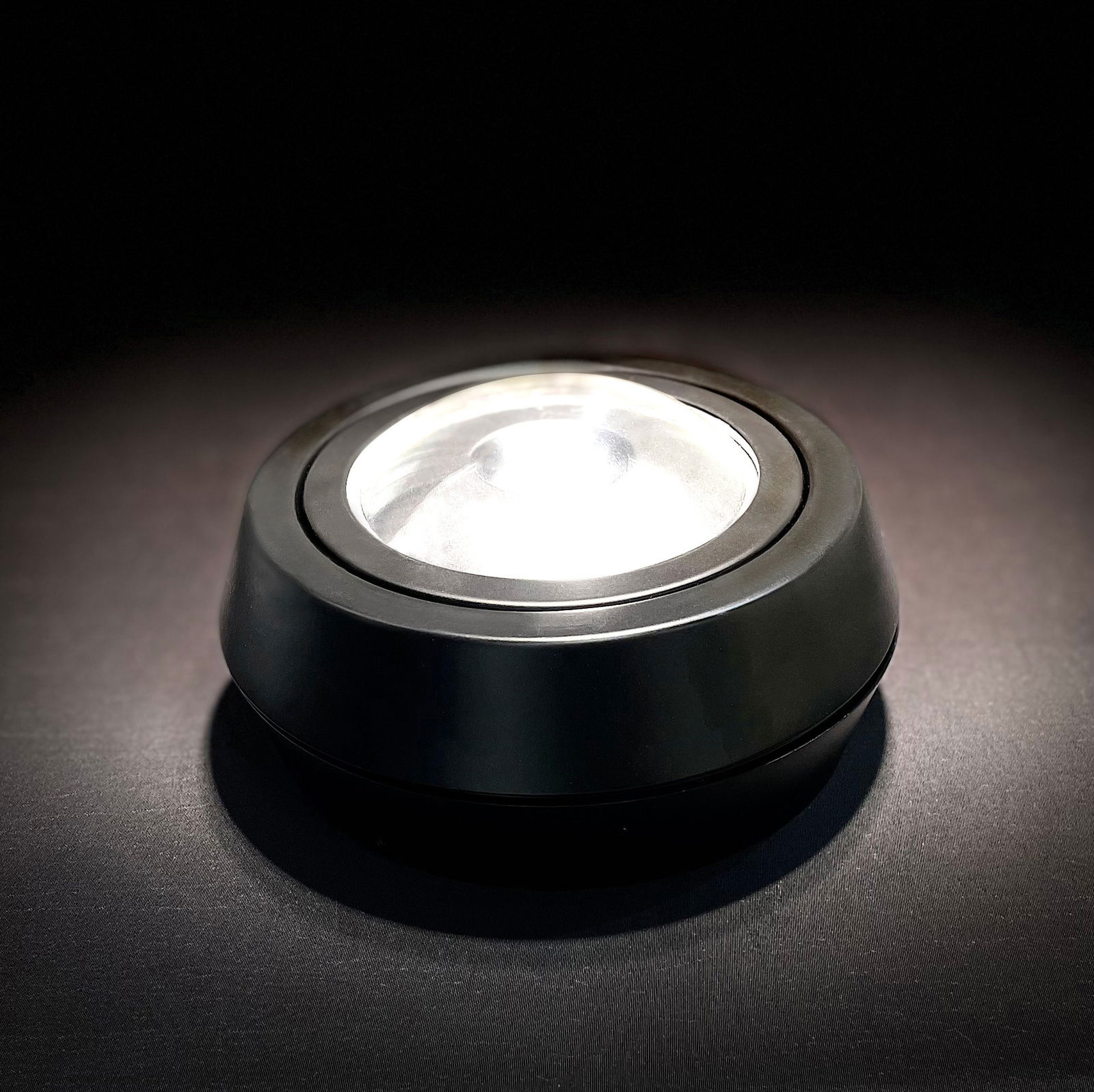 LED-Deckenleuchte SOLO MOVIMENTO in seitlicher Perspektive, schwarze runde Aufbauleuchte mit leuchtender Linse.