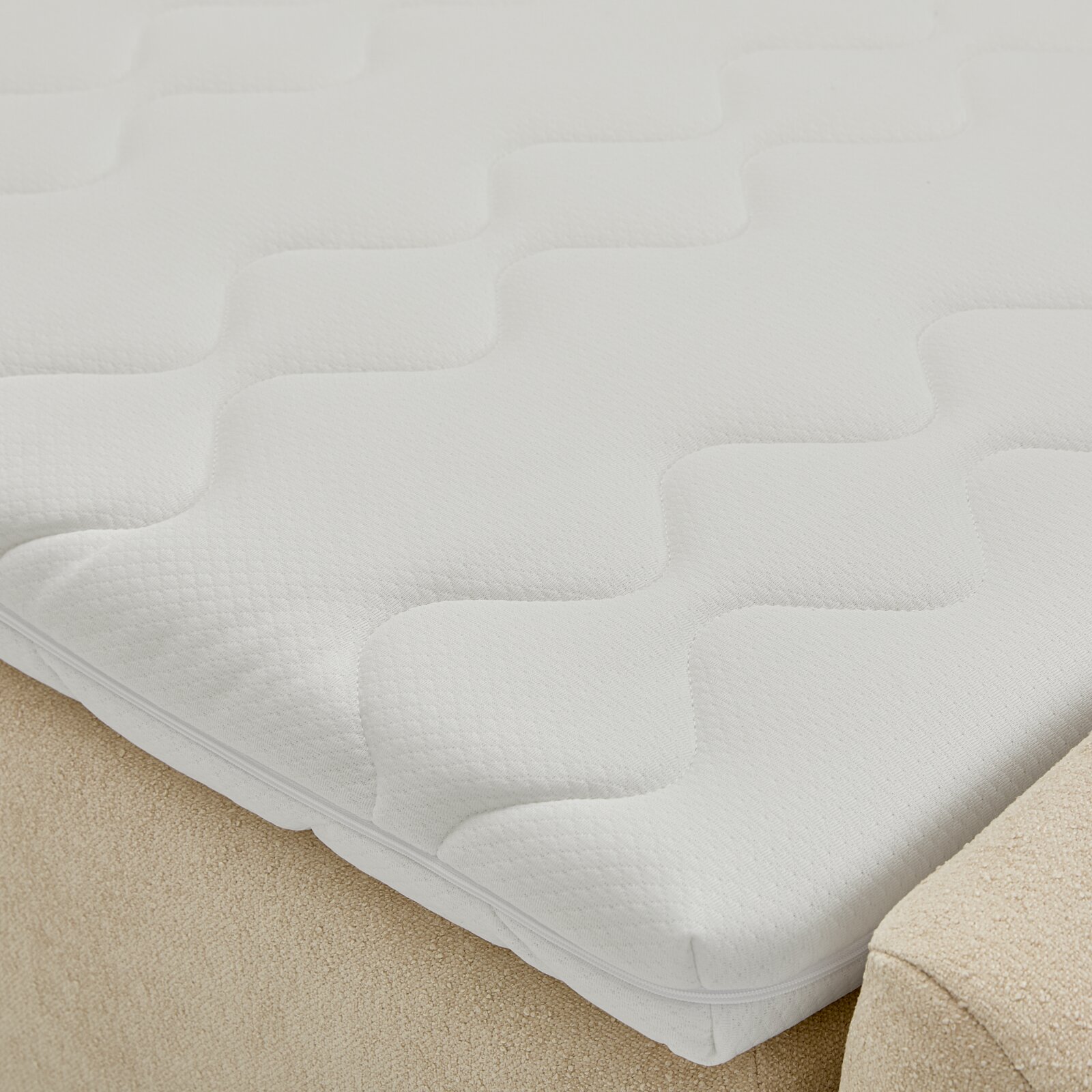 Nahaufnahme eines weißen Boxbetts mit strukturierter Oberfläche, von oben betrachtet.