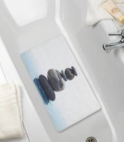 Perspektive von oben auf eine Wanneneinlage mit einem Zen-Steine-Motiv in einer Badewanne.