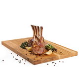 Schneidbrett aus Eiche mit Lammkoteletts, Spargel und Gewürzen, seitliche Perspektive