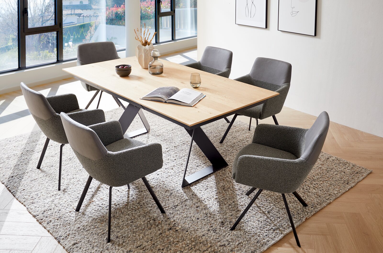 Venjakob Esstisch ETG61 Moderner Esstisch mit Holzplatte und schwarzen Metallbeinen, umgeben von sechs grauen Stühlen in einem hellen Raum mit großen Fenstern, aus der Vogelperspektive fotografiert.