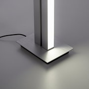Nahaufnahme der Basis einer modernen Stehleuchte PURE-LINES mit rechteckigem, gebürstetem Metallfuß und leuchtendem vertikalen Element.