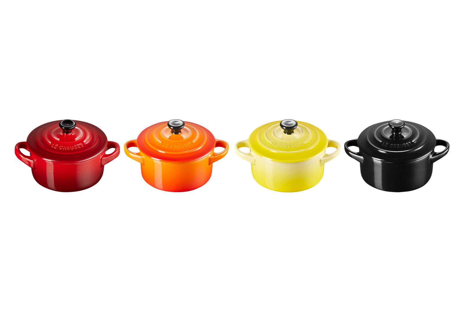 Vier Mini-Cocottes in verschiedenen Farben (Rot, Orange, Gelb, Schwarz) aus der Vogelperspektive.
