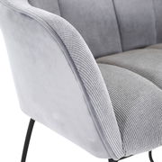 Nahaufnahme eines grauen Armlehnstuhls mit weichem Stoffbezug und schwarzen Metallbeinen, seitliche Perspektive