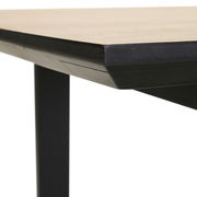 Nahaufnahme der Ecke eines Esstisches mit schwarzem Metallgestell und heller Tischplatte, seitliche Perspektive