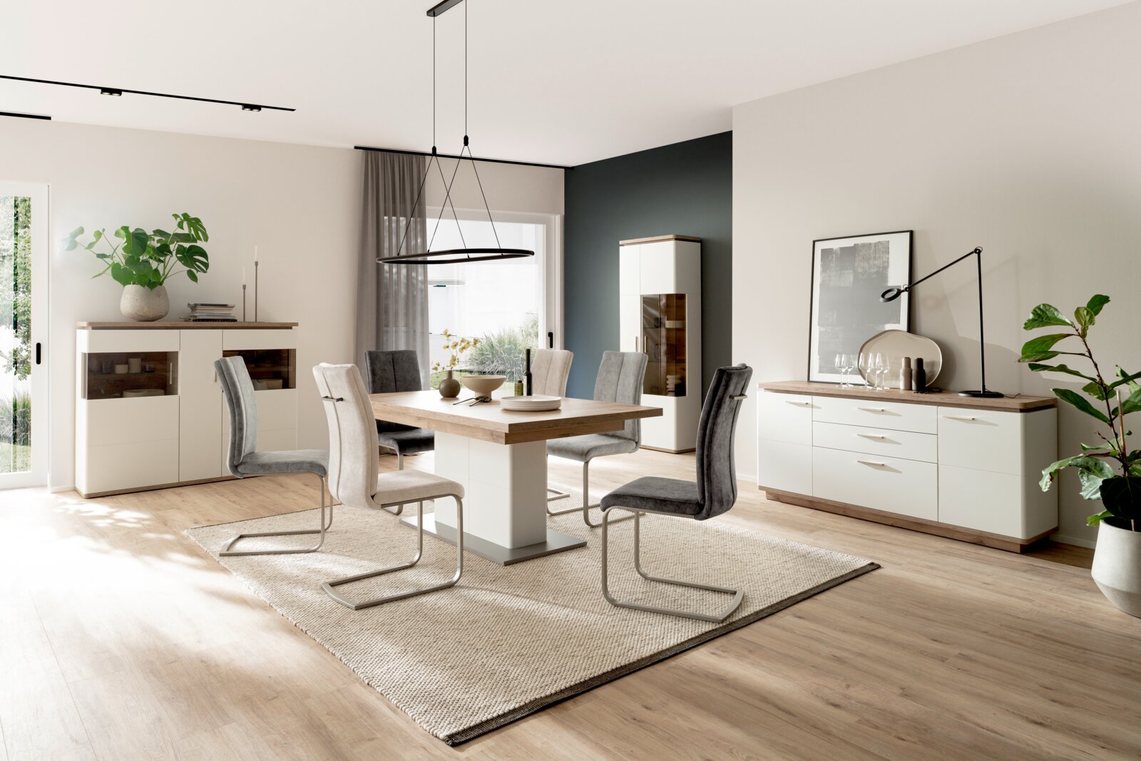 Moderne eetkamerset met een wit dressoir, vitrinekast en eettafel in houtlook, grijze klapstoelen en een ronde hanglamp op een licht tapijt – perspectief: frontale groothoekopname, licht van links.