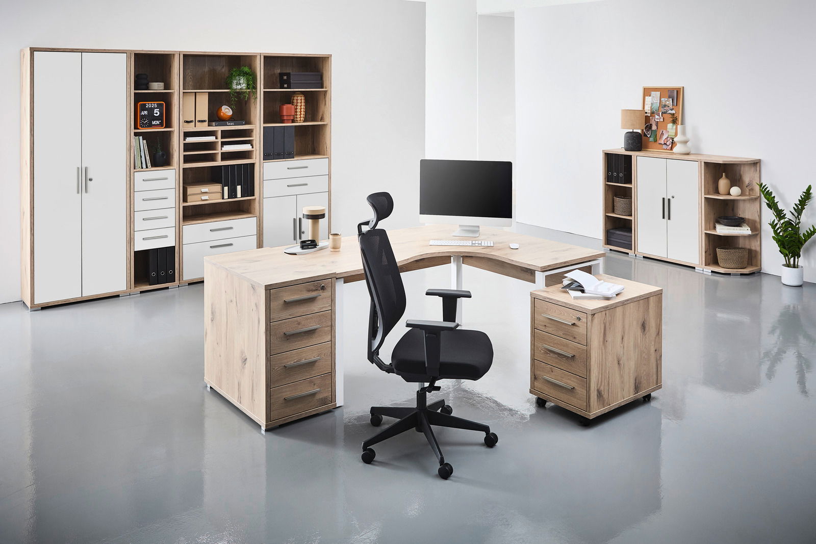 Voleo Eckschreibtisch CONNECT Moderne Büroumgebung mit einem Eckschreibtisch in Holzoptik, umgeben von Regalen und Schränken. Perspektive von vorne links.