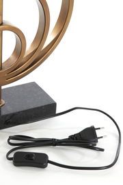 Nahaufnahme eines Lampenfußes mit geschwungenem, bronzefarbenem Design und schwarzem Kabel mit Schalter und Stecker.