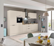 Moderne Einbauküche in heller Farbe mit integriertem Backofen und Kühlschrank, Dunstabzugshaube und Arbeitsplatte aus Holz. Perspektive von der Seite mit Blick auf den Esstisch im Vordergrund.