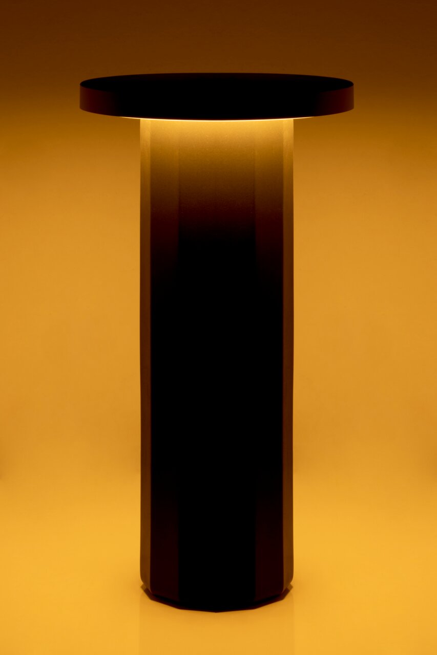 Moderne Akku-Tischleuchte mit zylindrischem Design, seitliche Perspektive, warmes Licht abstrahlend.
