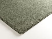 Nahaufnahme eines grünen Webteppichs Soft Dream, rechteckig, mit weicher Textur, von oben betrachtet.