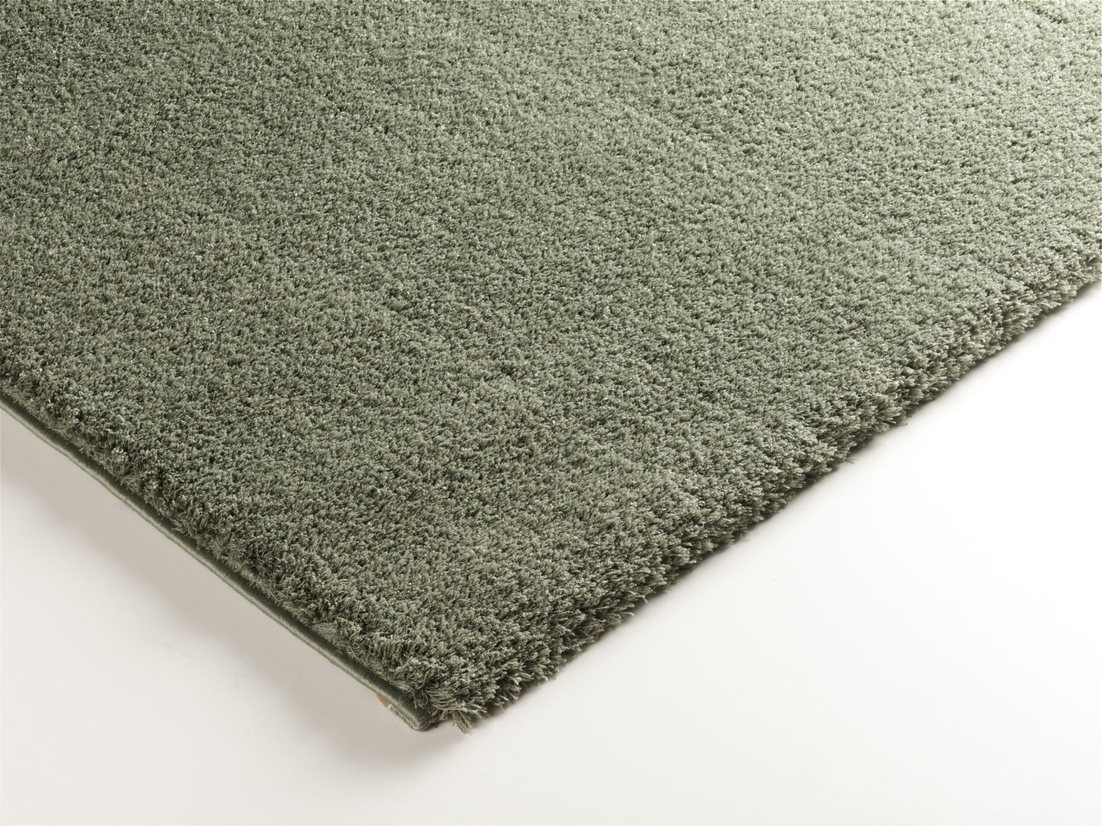 Nahaufnahme eines grünen Webteppichs Soft Dream, rechteckig, mit weicher Textur, von oben betrachtet.