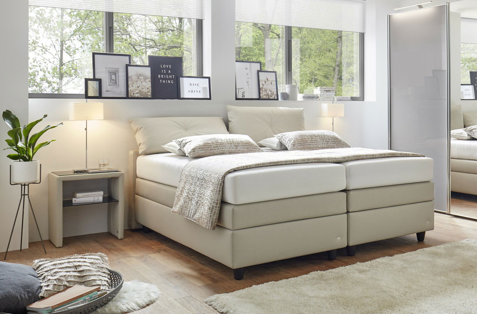 Modernes Boxspringbett in einem hellen Schlafzimmer, seitliche Perspektive