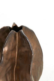 Nahaufnahme einer bronzefarbenen Vase mit organischer Form und strukturierter Oberfläche, von oben betrachtet.