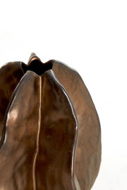 Nahaufnahme einer bronzefarbenen Vase mit organischer Form und strukturierter Oberfläche, von oben betrachtet.