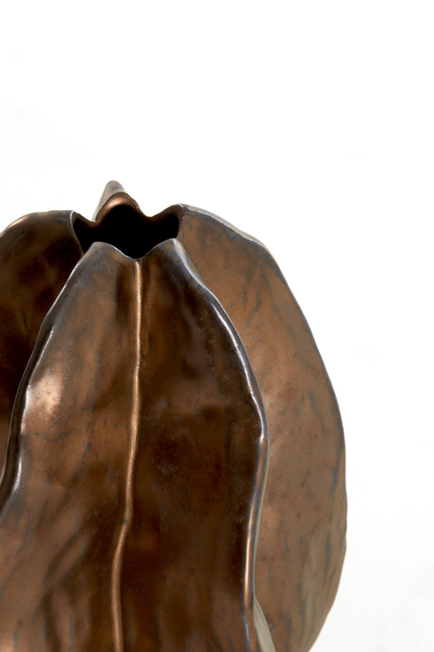 Nahaufnahme einer bronzefarbenen Vase mit organischer Form und strukturierter Oberfläche, von oben betrachtet.