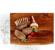 Vogelperspektive auf einen Hackblock aus Akazienholz mit gegrilltem Fleisch, Knoblauch und Tomaten als Dekoration.