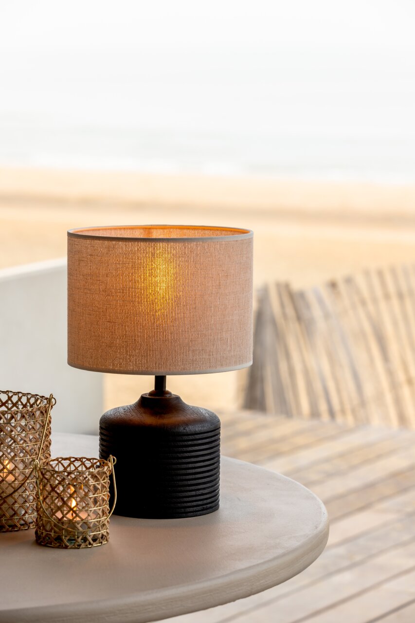 Light&Living Lampenschirm BRESKA Tischlampe mit beigem Stoffschirm und schwarzem, geripptem Sockel auf einem Tisch, seitliche Perspektive.