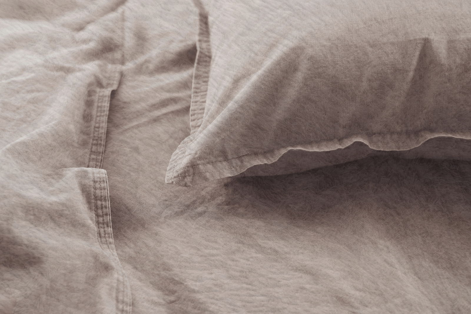 Nahaufnahme einer beigen Bettwäsche mit Kissenbezug, die eine weiche und strukturierte Oberfläche zeigt.