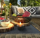 Solarleuchte in einem gemütlichen Gartenambiente, umgeben von Obst und dekorativen Kissen, aus der Perspektive eines niedrigen Tisches betrachtet.