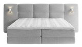 Frontale Ansicht eines grauen Boxspringbetts mit gepolstertem Kopfteil und integrierten Wandlampen.