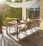 Moderner Gartentisch mit sechs Stühlen auf einer Terrasse, umgeben von grünen Pflanzen, aus seitlicher Perspektive fotografiert.