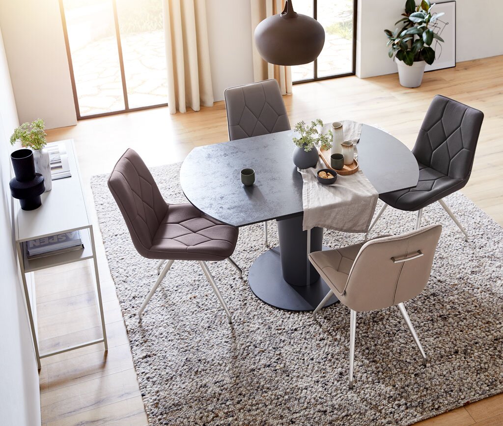 Esszimmer mit modernem Tisch und vier gepolsterten Stühlen in verschiedenen Farben, von oben betrachtet.