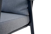 Close-up van een grijze Comfort Plus-stapelstoel met gestoffeerde zitting en rugleuning, gezien vanaf de zijkant
