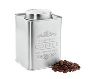 Silberne Vorratsdose für Kaffee mit dekorativem Schriftzug, abgebildet aus leicht seitlicher Perspektive, daneben Kaffeebohnen.