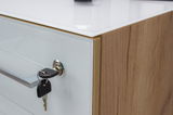 Nahaufnahme eines Aktenschranks mit Holzoptik und weißer Front, Schlüssel steckt im Schloss, seitliche Perspektive.